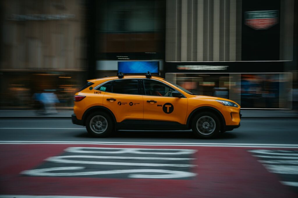 pexels-photo-27100698 A yellow NYC taxi speeds through the bustling city streets, capturing urban life in motion.
